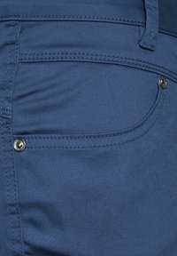 Námořnické modré džíny s přední kapsou, jemným prošíváním a kovovým detailem na knoflíku. Hladká textura a přiléhavý střih.