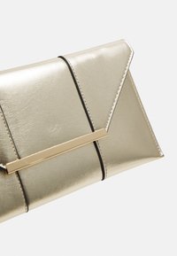 Clutch metallic oro con superficie texturizzata, caratterizzata da una linea nera e un dettagli di chiusura rettangolare dorata. Design a piega triangolare.