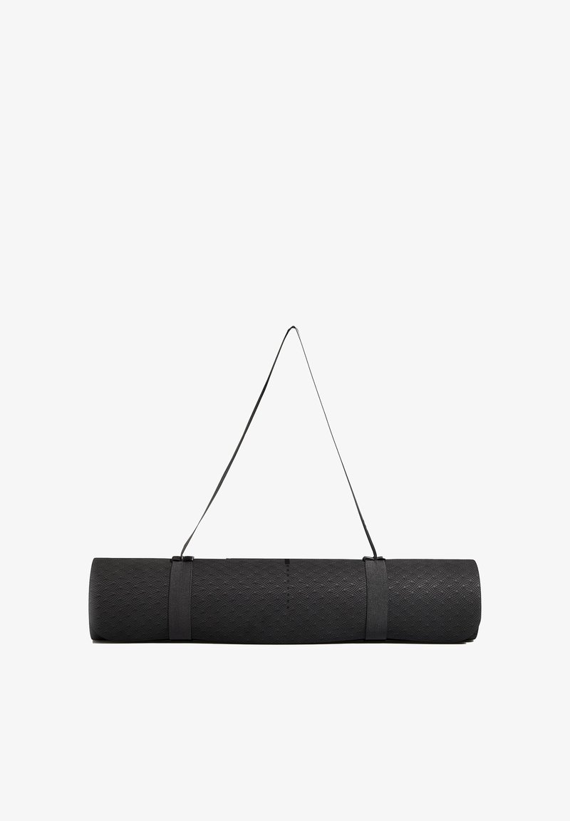 Fekete jóga matrac, amely fel van tekerve, texturált felülettel és hordozó pánttal. Halszálkamintás és masszív kivitelű.
