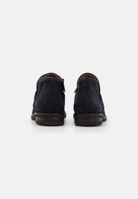 Botines de ante azul marino con una textura suave, cremallera trasera y una suela de goma negra ligeramente desgastada.