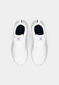 Weiße Sportschuhe mit einer strukturierten Oberfläche, Schnürdesign und kontrastierenden marineblauen Innensohlen. Mit Branding auf der Zunge und der Ferse.