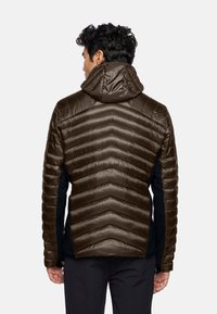 Giacca isolante marrone con motivo a chevron orizzontale, design con cappuccio, texture liscia e pannelli laterali neri per contrasto.