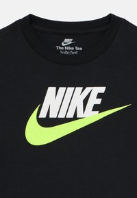 Maglietta nera Nike con logo "NIKE" bianco e swoosh giallo neon testurizzato. Design classico con collo rotondo. Morbido cotone.