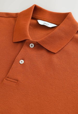 Rostfarbendes Polohemd aus strukturiertem Stoff, mit Kragen, einem Dreiknopfleiste und einer kleinen Brusttasche.