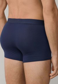Tmavomodré boxerkové slipy s hladkým povrchom a tesným strihom, ktoré disponujú širokým elastickým pásom a minimalistickým dizajnom.