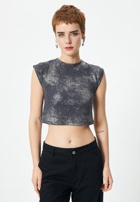Top navy corto con mangas cortas, que presenta un diseño texturizado y un sutil brillo metálico. Combinado con pantalones negros.