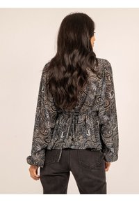 Blouse à manches longues avec un motif paisley en noir, marron et bleu, dotée d'une taille cintrée et de manches froncées. Fini en tissu texturé.