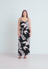 Robe maxi noire avec des motifs de feuilles tropicales blanches, bretelles spaghetti ajustables, détail de taille nouée et texture de tissu lisse.