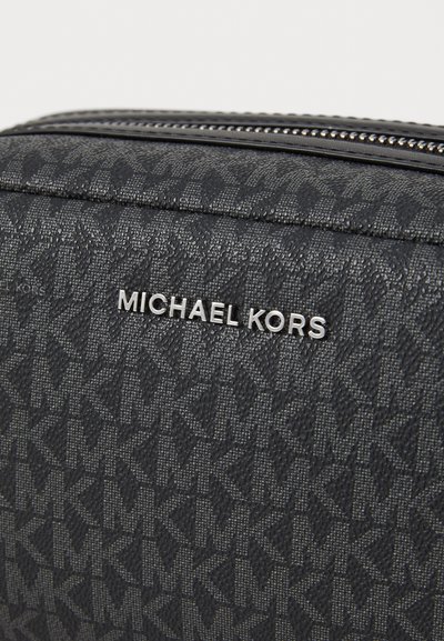 Sac noir texturé avec un motif monogramme, quincaillerie argentée et un logo "MICHAEL KORS" bien en vue à l'avant.