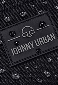 Tessuto nero con texture e gocce d'acqua, con un'applique nera recante la scritta "JOHNNY URBAN" in lettere grigie.