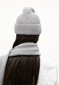 Grijze gebreide beanie met een geribde textuur en omgeslagen rand, gecombineerd met een bijpassende geribde sjaal. Beide artikelen zijn gemaakt van zachte draad.