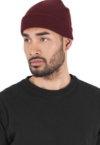 Burgunderfarget strikket lue med ribbestruktur, båret over en svart crewneck skjorte. Enkel design, tettsittende stil.