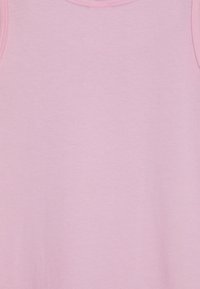 Jasnoróżowy top na ramiączkach z gładkiego materiału bawełnianego, z okrągłym dekoltem i bez widocznych wzorów czy dodatków. Prosty i minimalistyczny design.