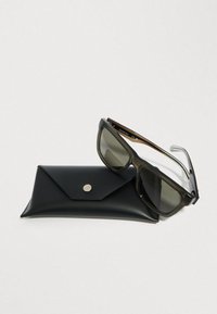 Okulary przeciwsłoneczne z ciemnobrązową plastikową oprawką i szarymi szkłami, leżące na czarnym skórzanym etui z srebrnym zatrzaskiem.