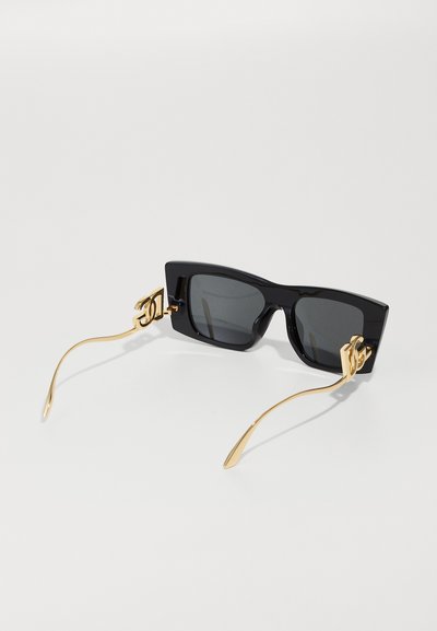 Black square sunglasses with dark lenses, gold accents on the arms, and a glossy finish. Arms shaped with a slight curve and thin silhouette.