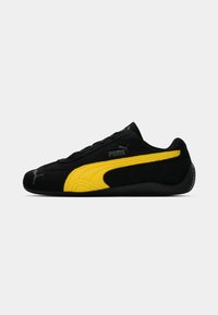 Sneaker nere in suede con un accento giallo, caratterizzati da un profilo basso, punta rotonda, finitura testurizzata e logo Puma sul lato.