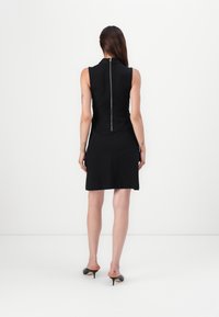 Black sleeveless dress with a fitted bodice and flared skirt. Features a back zipper and smooth texture. High neckline and minimal design.