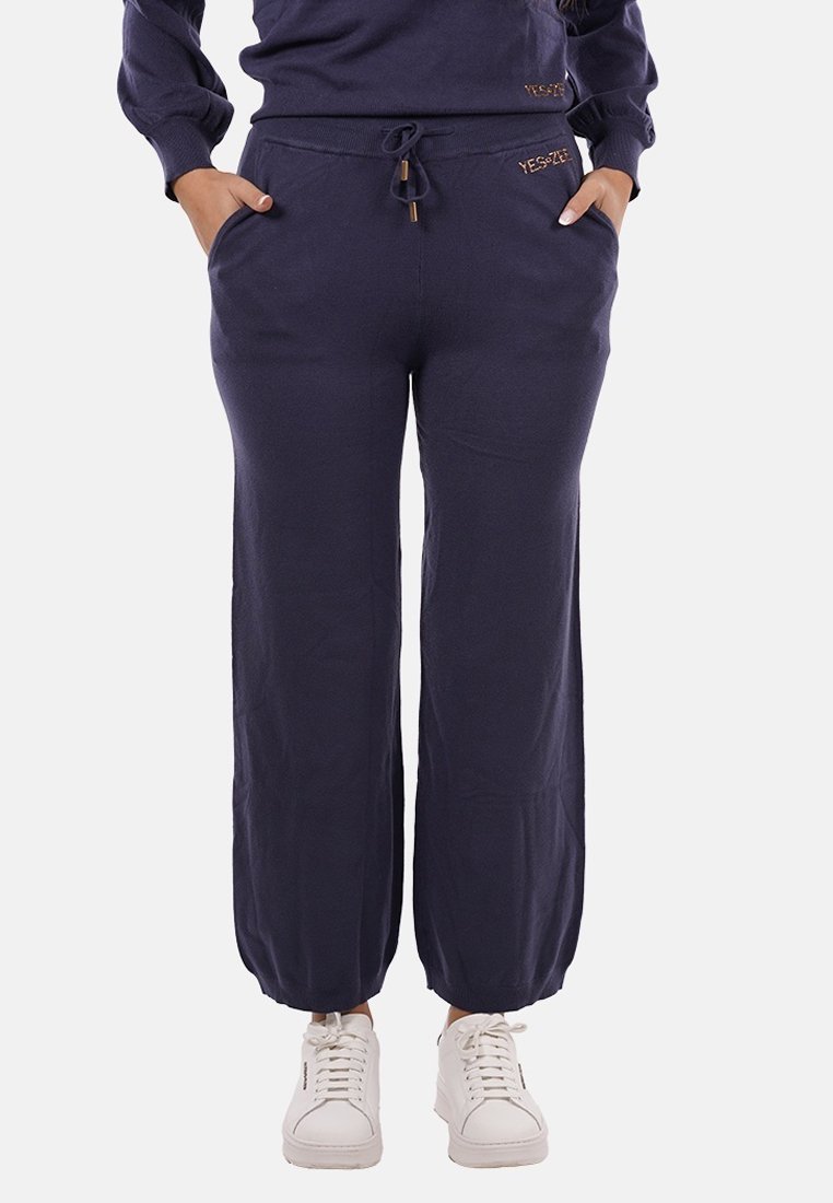 Pantaloni tuta blu navy con polsini elastici, vita con cordoncino e tasche laterali. Realizzati in morbido tessuto con una superficie liscia.