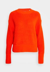 Jasnopomarańczowy sweter wykonany z teksturowanej dzianiny. Posiada okrągły dekolt, ściągacze na mankietach oraz krótki fason.