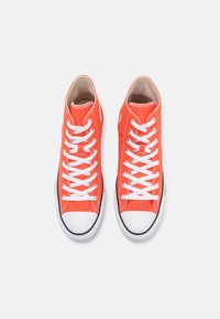 Hochtop-Sneaker aus leuchtend orangefarbenem Canvas mit weißen Schnürsenkeln, klassischer Gummispitze und schwarzen Sohlen-Details. Glatte Textur mit kontrastierenden Nähten.