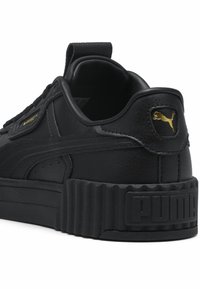 Schwarze Leder-Sneaker mit strukturierter schwarzer Plateau-Sohle, ausgestattet mit einem goldenen Logo-Akzent und einem abgerundeten Absatz mit Nähdetails.