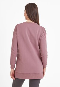 Long-sleeve pullover in soft pink fabric, featuring a relaxed fit, ribbed cuffs, a scoop neckline, and side slits at the hem.
