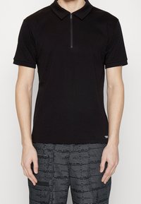 Černé polo tričko s krátkým zipem, krátkými rukávy a slim fit střihem, vyrobené z hladkého, lehkého materiálu.