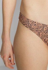 Parte de baixo de biquíni com padrão de onça em tons de laranja e preto. Tecido suave com uma cintura baixa e corte curvo para um look ajustado.