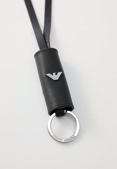 Black leather keychain holder features a silver ring and an embossed eagle logo. Textured surface with smooth accents.
