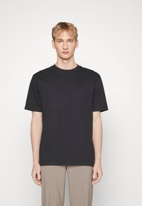 Tricou din bumbac negru, cu guler rotund și mâneci scurte, având o croială lejeră și o textură netedă. Fără model sau logo-uri vizibile.