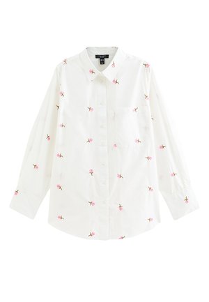 Chemise blanche à manches longues avec boutons, décorée de petites broderies de roses roses dispersées sur le tissu et une poche poitrine unique.