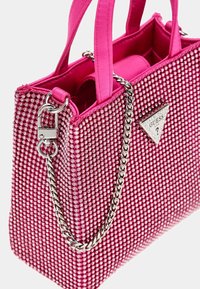 Vaaleanpunainen käsilaukku, jossa on teksturoidun pinnan rikas koristelu strasseilla, kaksi kangasottoa ja hopeinen ketjuolka. Kolmion muotoinen brändilogo läsnä.