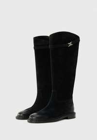 Botas altas de ante negro hasta la rodilla con punta de piel lisa, que cuentan con una correa decorativa cerca de la parte superior y un sutil detalle metálico.