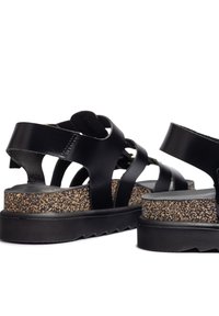 Sandalias de cuero negro con plantilla de corcho, correas ajustables y una suela de goma texturizada para mayor tracción.