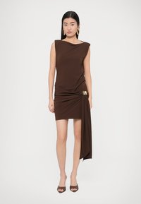 Pruun varrukateta kleit drapeeritud disainiga ja külje sõlmega, kuldse aktsendiga. Sile, veniv kangas, keha järgiva lõikega.