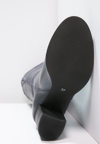 Bottine en cuir gris avec un talon bloc et une semelle en caoutchouc noire texturée. Affiche la taille 37, mettant en valeur un design lisse et structuré.