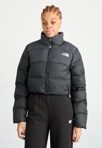 Černá zkrácená péřová bunda s vysokým límcem, s předním zipem a logem North Face na levé části hrudi. Hladká, lesklá textura.