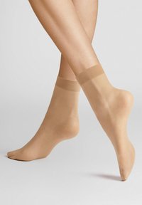 Beige Knöchelstrümpfe aus durchscheinendem Nylonmaterial mit einem weichen, elastischen Bündchen. Sie verfügen über eine glatte Textur und ein klassisches Design.