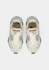 Baskets Lacoste avec un mélange de matières en maille et synthétiques blanches, crèmes et vertes, dotées de lacets, de motifs texturés et d'un logo sur la languette.