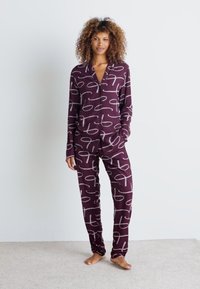 Conjunto de pijama burdeos en tejido suave con un patrón abstracto blanco. Incluye una camisa de botón con cuello y pantalones elásticos.