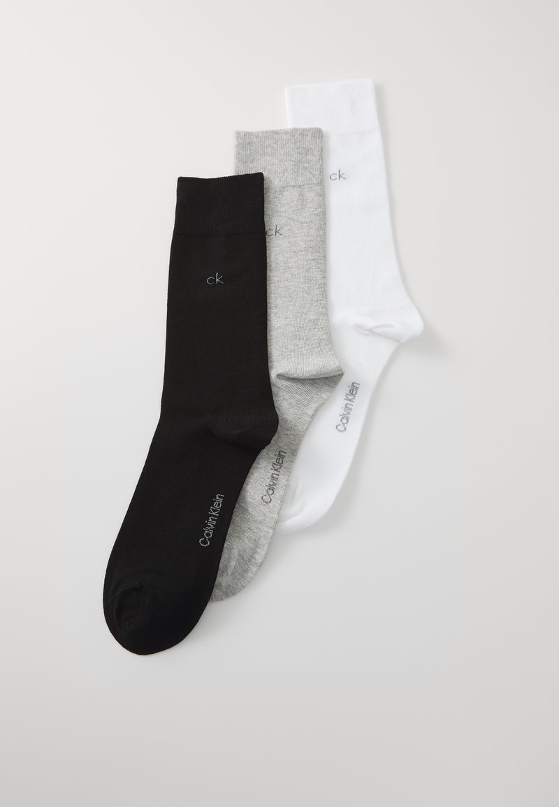 Drei Paar Knöchelsocken in Schwarz, Grau und Weiß. Jede Socke hat einen gerippten Bund und zeigt das "ck"-Logo in einer kontrastierenden Farbe.