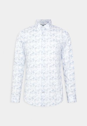 Chemise blanche à manches longues boutonnée avec motif floral bleu clair et col pointu sur un fond uni clair.