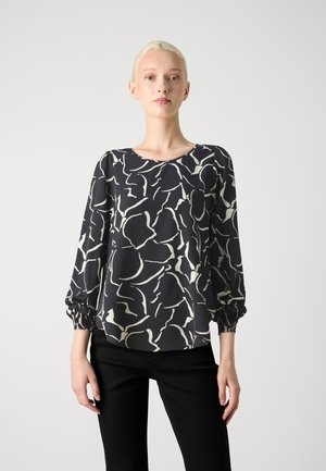 Blusa estampada en blanco y negro con mangas largas abullonadas y un escote redondo, confeccionada en tela suave y con puños fruncidos.