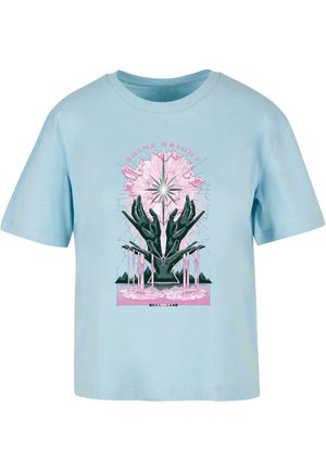 Lyseblå bomulds t-shirt med grafisk design med sorte hænder, en pink stjernespand og teksten "SHINE BRIGHT" ovenfor. Korte ærmer og rund hals.