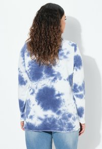 Camisa de manga larga de teñido anudado en azul y blanco. Tejido suave, corte relajado, con un dobladillo redondeado y sin adornos ni acentos notables.