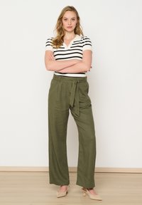 Green wide-leg pants with a tie waist, paired with a black and white striped short-sleeve top. Smooth fabric, relaxed fit, and simple design.