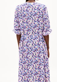 Kukkamekossa on monivärinen kuvio, joka sisältää vaaleanpunaisen, sinisen ja violetin sävyjä. Mekko on valmistettu kevyestä kankaasta, ja siinä on vyökoristus.