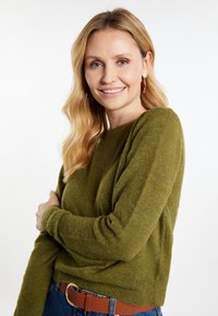 Maglione verde oliva realizzato in morbido tessuto a maglia testurizzato, con una vestibilità comoda e maniche lunghe. Abbinato a una cintura marrone e a un paio di jeans.