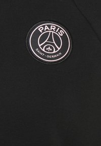 Tessuto nero con una toppa ricamata circolare che riporta "PARIGI" e "SAINT-GERMAIN" in testo rosa, insieme a un logo iconico.