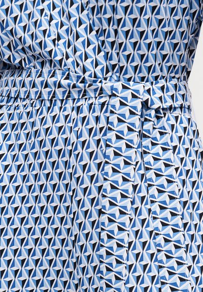 Ύφασμα με γεωμετρικό σχέδιο σε μπλε, λευκό και μαύρο χρώμα με δεμένη ζώνη γύρω από τη μέση σε πλισέ ένδυμα.